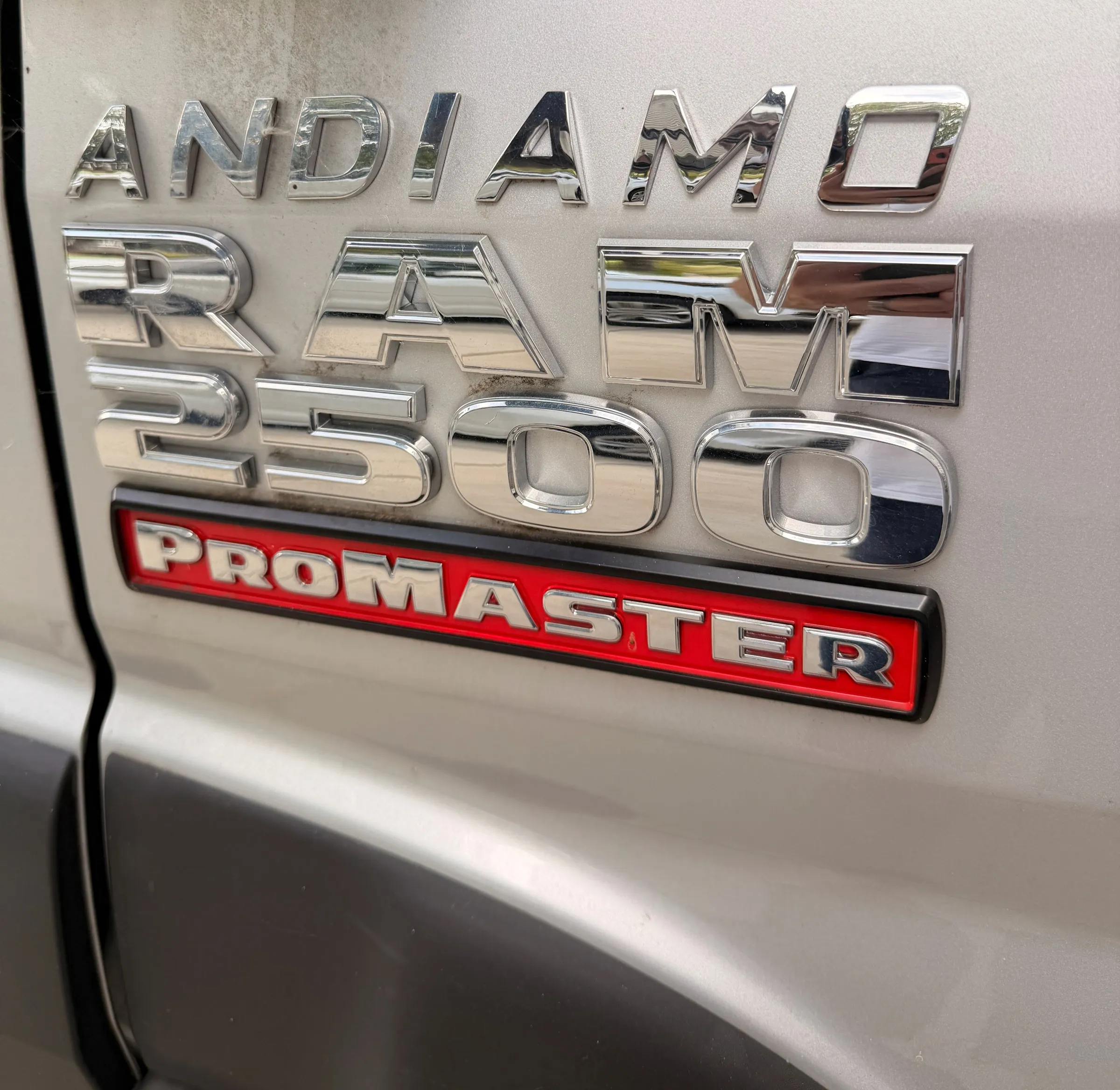 Chrome "ANDIAMO" badge above the RAM 2500 and red PROMASTER badges on the silver van door