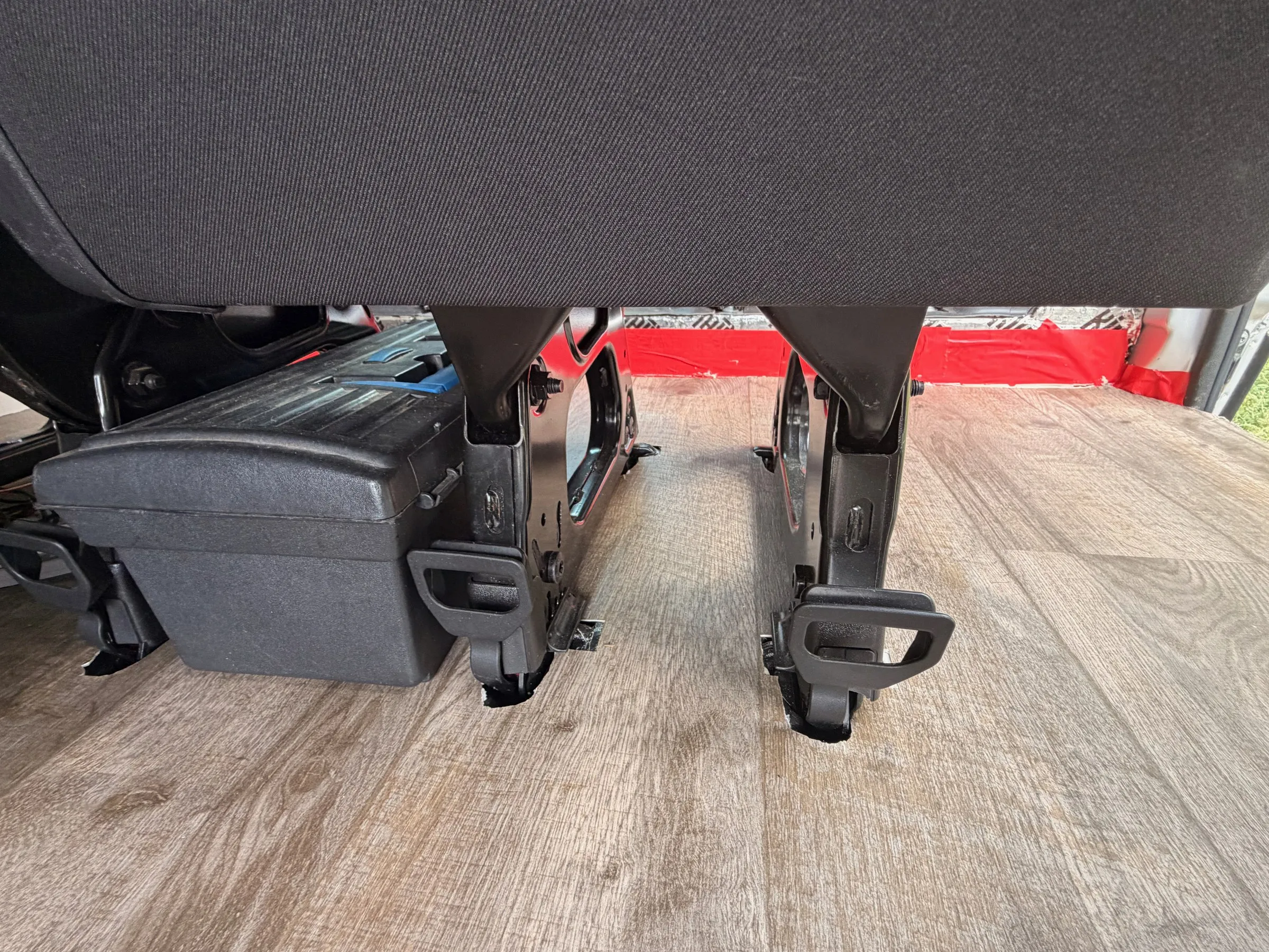 Close-up of the black quick-release seat legs locked into the floor beside a storage box