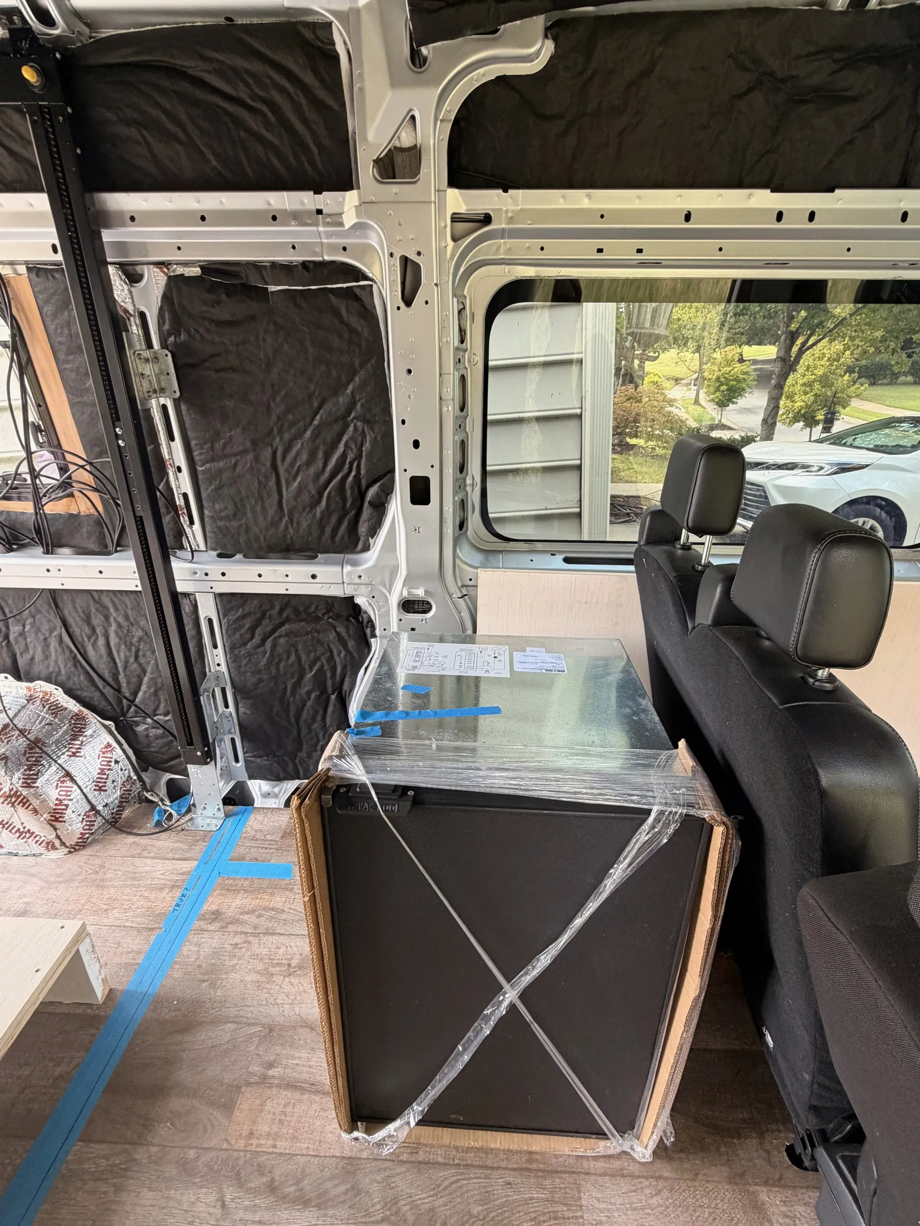 New Nova Kool refrigerator, still in protective wrap, standing beside the rear passenger seats