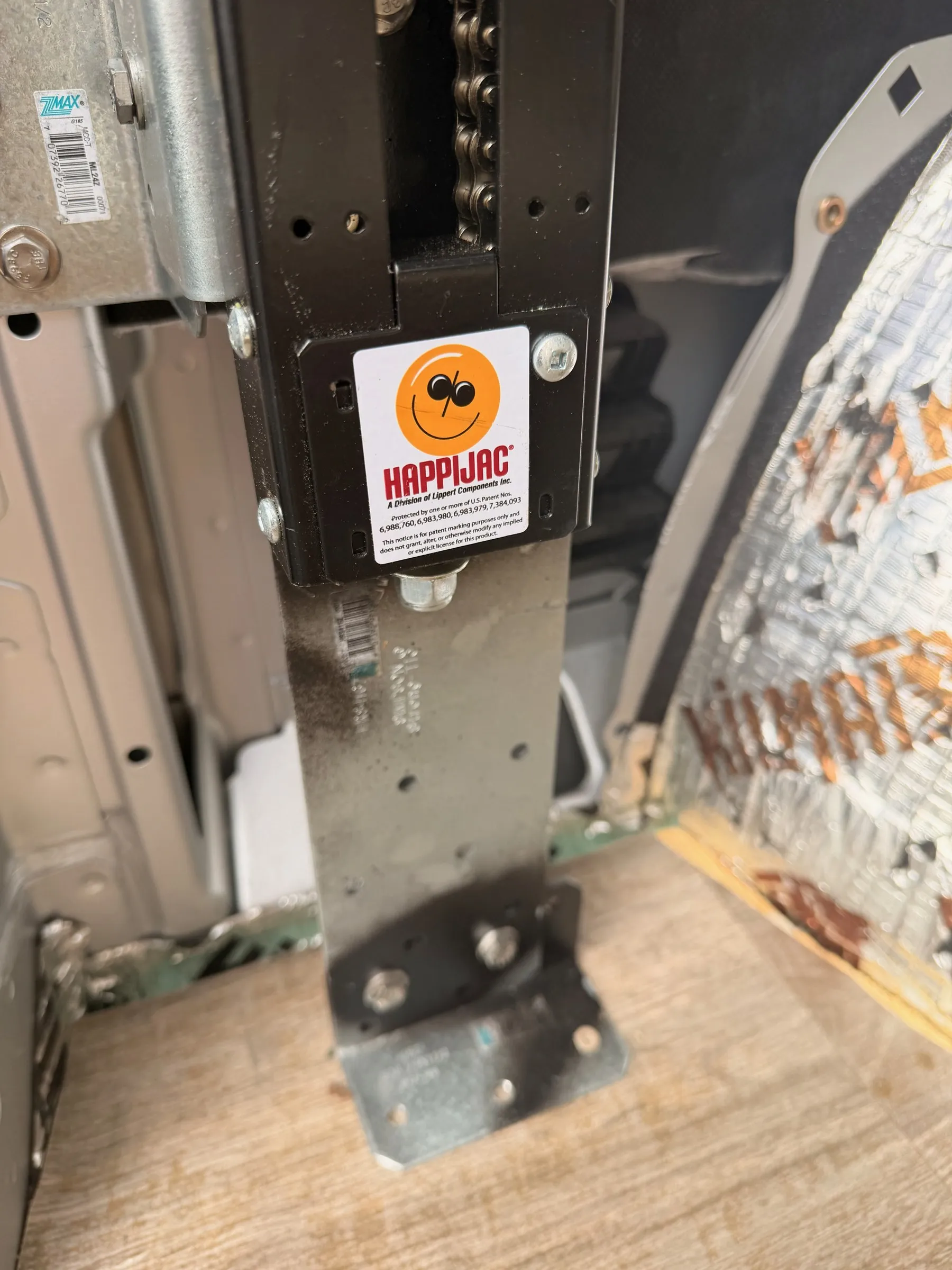 Happijac bed-lift column with chain drive mounted to the floor beside the insulated wheel well